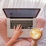 Person using MacBook Pro and holding cappuccino