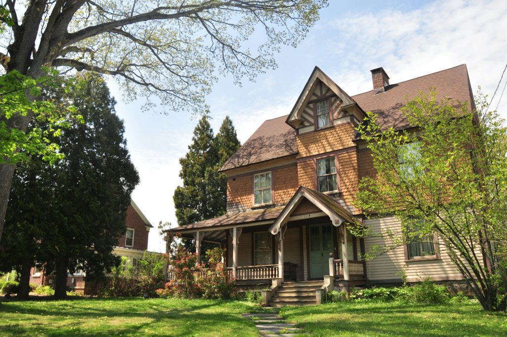 Brown brick house near green grass field and trees during daytime