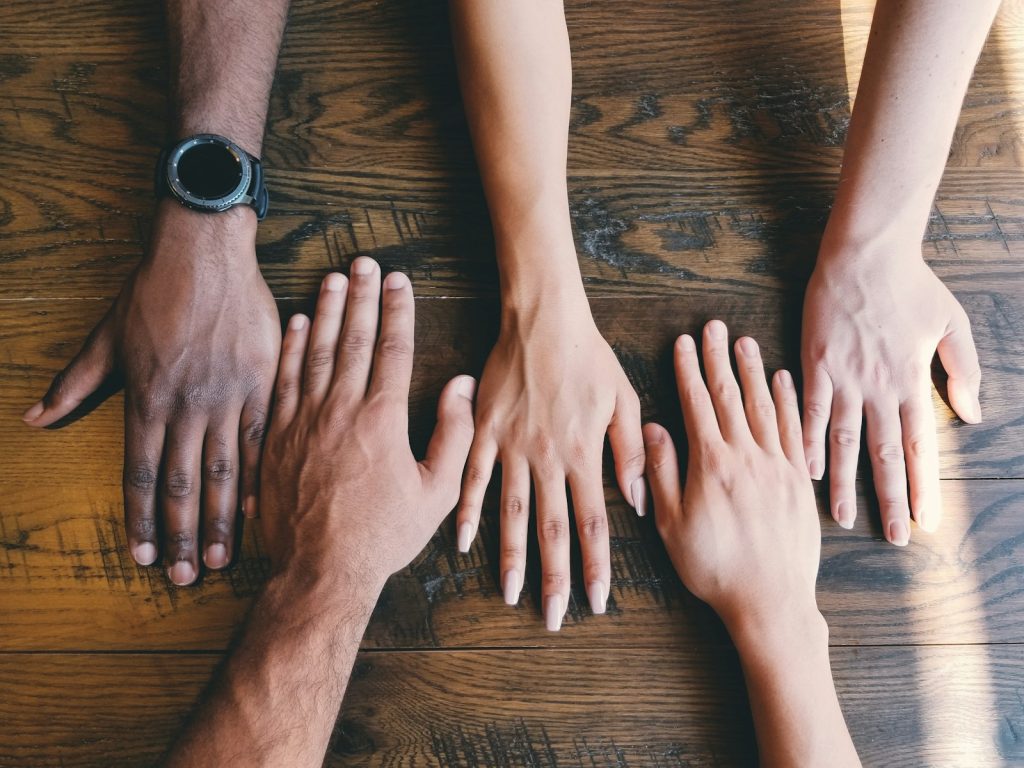 Diversity in five human hands on brown surface